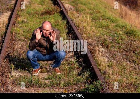 L'uomo premuroso siede su binari. La persona sconvolta in uno stress. Stress concettuale, fallimento della vita, problema. Triste maschio Foto Stock