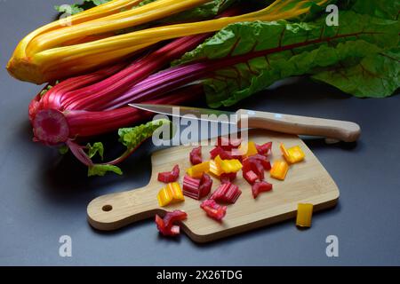 Bietola svizzera, steli tritati su tavola di legno con coltello, Beta vulgaris Foto Stock