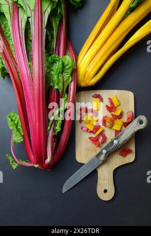 Bietola svizzera, steli tritati su tavola di legno con coltello, Beta vulgaris Foto Stock