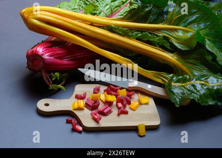 Bietola svizzera, steli tritati su tavola di legno con coltello, Beta vulgaris Foto Stock