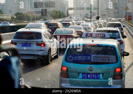 Shanghai, Repubblica Popolare Cinese, traffico intenso con molte auto in una strada cittadina con il sole, Shanghai, Cina Foto Stock