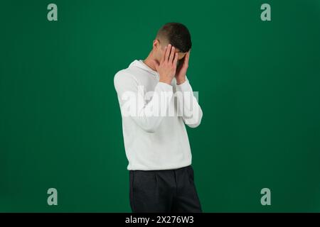 emozioni di un bell'uomo su sfondo verde cromakey primo piano capelli scuri giovane uomo. stress da uomo d'affari da tutto Foto Stock