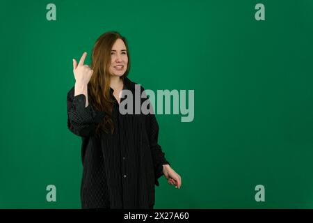 donna adolescente in una foto in studio con sfondo verde che fa posa. espressioni facciali Foto Stock