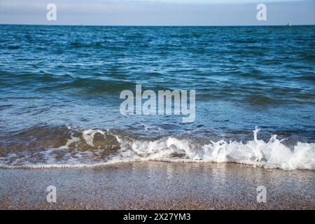 Spiaggia di Llevant, Barcellona, Spagna, in una giornata di sole, onde e mare, cielo azzurro, sabbia, ciottoli e rocce, vibrazioni estive, madre natura, felice giornata della Terra Foto Stock