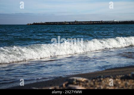 Spiaggia di Llevant, Barcellona, Spagna, in una giornata di sole, onde e mare, cielo azzurro, sabbia, ciottoli e rocce, vibrazioni estive, madre natura, felice giornata della Terra Foto Stock