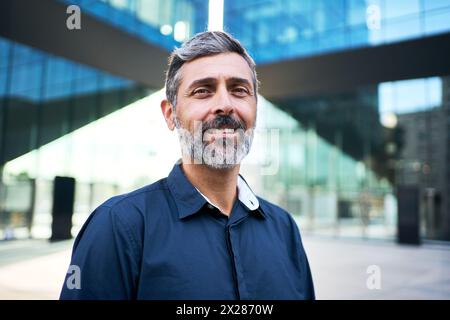 Uomo d'affari maturo dai capelli grigi che sorride alla macchina fotografica con un atteggiamento positivo nella camicia vestito. Foto Stock