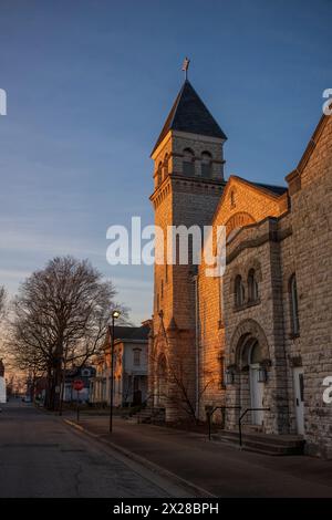 Il bagliore del tramonto splende sul campanile di una chiesa cattolica in ciottoli, situata nel Midwest degli Stati Uniti di Vincennes, Indiana. Foto Stock