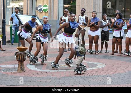 Gruppo di ragazzi e ragazze di colore in costume locale che eseguono una tipica danza africana nel centro di città del Capo, in Sudafrica Foto Stock