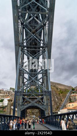 Turisti che camminano lungo la piattaforma inferiore con vista sulla struttura metallica del ponte in acciaio Don Luis i e sulla piattaforma superiore di Porto con la pioggia Foto Stock
