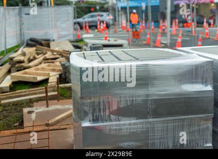 Mattoni avvolti in plastica in un cantiere edile. Lavoratore irriconoscibile che mantiene il traffico in movimento. Auckland. Foto Stock