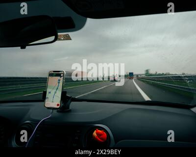 Smartphone 5g con visualizzazione della navigazione GPS montato sul cruscotto di un'auto, A1 A8 vicino a Milano, Italia Foto Stock