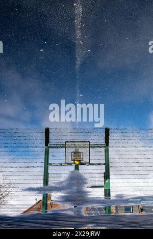 Canestro da basket che si riflette in una pozzanghera Foto Stock