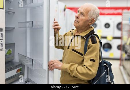 Pensionato Senor MAN che acquista un frigorifero nello showroom del negozio di elettrodomestici Foto Stock