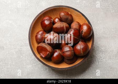 Castagne dolci fresche commestibili in una ciotola di legno su un tavolo grigio, vista dall'alto Foto Stock