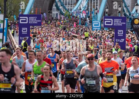 Tower Hill, Londra, Regno Unito. 21 aprile 2024. Circa 50.000 persone partecipano alla maratona TCS di Londra del 2024, tra cui i migliori runner e gli atleti in sedia a rotelle del mondo. Le masse di corridori del club e del divertimento li seguono, con molti che raccolgono grandi somme per beneficenza e spesso corrono in abiti eleganti e puntano al Guinness dei primati per varie classi. Massa di corridori che attraversano il Tower Bridge Foto Stock