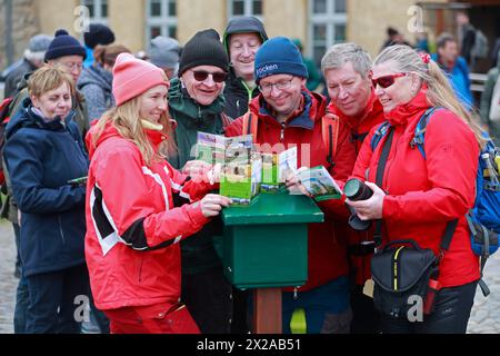 21 aprile 2024, Sassonia-Anhalt, Osterwieck: I partecipanti all'Harz Hiking Needle si trovano di fronte a un francobollo a Wasserburg Zilly. Nuovi opuscoli a tema e i nuovi pass escursionistici per il 2024 sono stati presentati all'apertura della stagione Harz Hiking Needle a Wasserburg Zilly. Centinaia di escursionisti sono venuti per celebrare il nuovo anno delle escursioni nelle montagne Harz. Fin dalla sua fondazione, l'Harzer Wandernadel si è sviluppato in un importante fattore economico per il turismo. Ogni anno vengono pubblicati oltre 100.000 opuscoli escursionistici. Un totale di 222 francobolli possono essere raccolti nei luoghi di interesse lungo il percorso designato Foto Stock