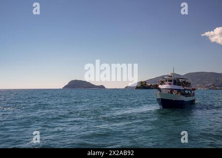 Crociera in nave con i turisti contro Marathonisi, conosciuta anche come l'isola delle tartarughe nella baia di laganas, famosa per le tartarughe marine a Zante, Zante, Grecia Foto Stock