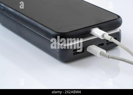 Un telefono cellulare collegato a una batteria esterna tramite un cavo usb per la ricarica Foto Stock