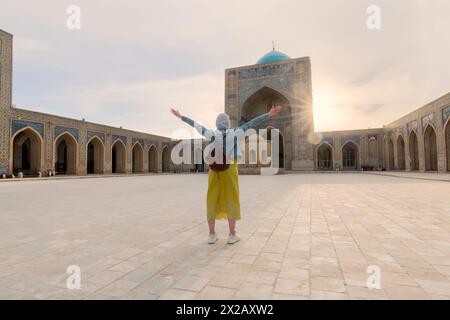 Giovane turista con le braccia all'interno della moschea di Kalyan, parte del complesso po-i-Kalyan a Bukhara, Uzbekistan Foto Stock