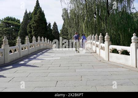 Nuovo Palazzo d'Estate, Pechino, Cina, Asia, due persone attraversano un ponte con ringhiere bianche accanto agli alberi verdi, Pechino Foto Stock