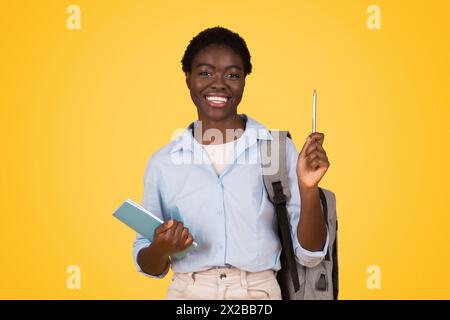 Felice studentessa afroamericana che punta verso l'alto Foto Stock