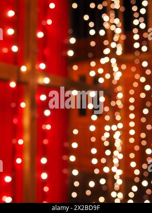 Bokeh la sera di Natale. Bellissimi bokeh rotondi. Rosso, giallo, oro, bianco al buio. Le feste fanno da sfondo per il nuovo anno, buon Natale Foto Stock