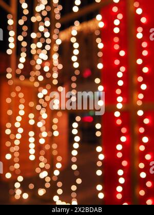 Bokeh la sera di Natale. Bellissimi bokeh rotondi. Rosso, giallo, oro, bianco al buio. Le feste fanno da sfondo per il nuovo anno, buon Natale Foto Stock