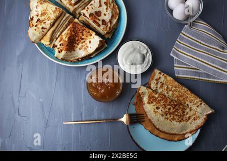 Colazione con frittelle dolci crepe su piatto e piatto con forchetta accanto alla marmellata di panna acida Foto Stock