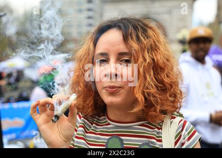 Una giovane donna fuma uno spinello durante i festeggiamenti del 420 al Washington Square Park di New York, N.Y., sabato 20 aprile 2024. Le persone di tutto il mondo celebrano il loro piacere colpevole preferito: La marijuana. (Foto: Gordon Donovan) Foto Stock
