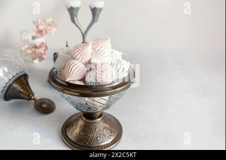 Piccole meringhe bianche in un piatto bianco sul tavolo. Spazio di copia. Foto Stock