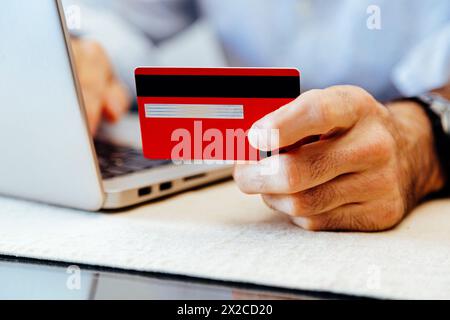 Uomo che effettua pagamenti online tramite carta di credito o debito sul laptop. Foto Stock