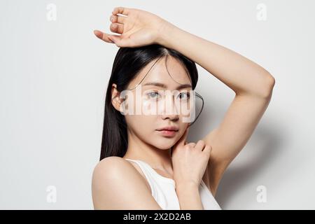 Una donna asiatica che guarda dritto con le mani sulla testa Foto Stock
