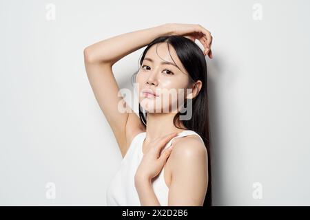 Una donna asiatica che guarda dritto con le mani sulla testa Foto Stock