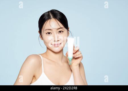 Donna asiatica posa con White Eye Cream Foto Stock