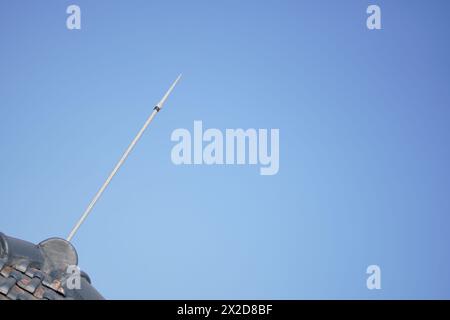 Un dispositivo di protezione dai fulmini installato sulle tegole di una casa con un cielo blu come sfondo Foto Stock