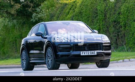 Bicester, Regno Unito - 21 aprile 2024: 2022 auto d'epoca elettrica ibrida Porsche Cayenne che guida su una strada britannica Foto Stock