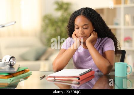 Studente nero che studia note difficili da leggere a casa Foto Stock