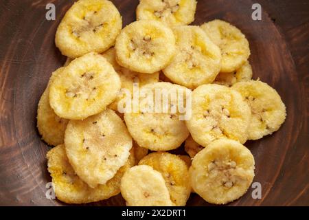 Vista dall'alto delle banane biologiche essiccate in una ciotola marrone di legno. Primi piani di frutta secca croccante. Foto Stock