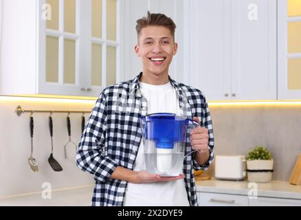 Uomo felice con la caraffa del filtro dell'acqua in cucina Foto Stock