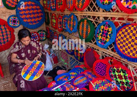 Narayanganj, Dacca, Bangladesh. 22 aprile 2024, Narayanganj, Dacca, Bangladesh: I lavoratori ricamano sapientemente ventilatori a mano con forme geometriche dai colori vivaci a Narayanganj, Bangladesh. Utilizzano bambù e filati colorati per creare ventilatori dal design complesso. Durante le estati calde, danno una brezza fresca che aiuta quando fa davvero caldo all'aperto in caso di distacco del carico. Ogni lavoratore può contare su 10 tifosi al giorno, ogni fan viene venduto per circa 1,20 USD alle fiere dei villaggi. Questa è diventata una professione tradizionale nella zona, fanno fan a mano da centinaia di anni. Credito: ZUMA Press, in Foto Stock