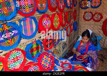 Narayanganj, Dacca, Bangladesh. 22 aprile 2024, Narayanganj, Dacca, Bangladesh: I lavoratori ricamano sapientemente ventilatori a mano con forme geometriche dai colori vivaci a Narayanganj, Bangladesh. Utilizzano bambù e filati colorati per creare ventilatori dal design complesso. Durante le estati calde, danno una brezza fresca che aiuta quando fa davvero caldo all'aperto in caso di distacco del carico. Ogni lavoratore può contare su 10 tifosi al giorno, ogni fan viene venduto per circa 1,20 USD alle fiere dei villaggi. Questa è diventata una professione tradizionale nella zona, fanno fan a mano da centinaia di anni. Credito: ZUMA Press, in Foto Stock