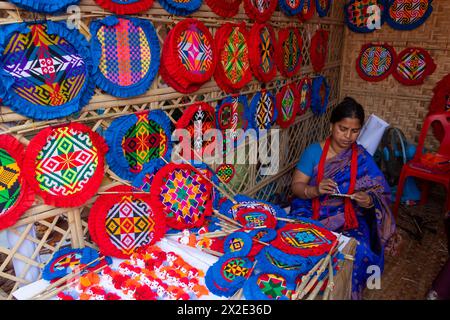 Narayanganj, Dacca, Bangladesh. 22 aprile 2024, Narayanganj, Dacca, Bangladesh: I lavoratori ricamano sapientemente ventilatori a mano con forme geometriche dai colori vivaci a Narayanganj, Bangladesh. Utilizzano bambù e filati colorati per creare ventilatori dal design complesso. Durante le estati calde, danno una brezza fresca che aiuta quando fa davvero caldo all'aperto in caso di distacco del carico. Ogni lavoratore può contare su 10 tifosi al giorno, ogni fan viene venduto per circa 1,20 USD alle fiere dei villaggi. Questa è diventata una professione tradizionale nella zona, fanno fan a mano da centinaia di anni. Credito: ZUMA Press, in Foto Stock