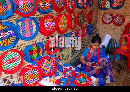 Narayanganj, Dacca, Bangladesh. 22 aprile 2024, Narayanganj, Dacca, Bangladesh: I lavoratori ricamano sapientemente ventilatori a mano con forme geometriche dai colori vivaci a Narayanganj, Bangladesh. Utilizzano bambù e filati colorati per creare ventilatori dal design complesso. Durante le estati calde, danno una brezza fresca che aiuta quando fa davvero caldo all'aperto in caso di distacco del carico. Ogni lavoratore può contare su 10 tifosi al giorno, ogni fan viene venduto per circa 1,20 USD alle fiere dei villaggi. Questa è diventata una professione tradizionale nella zona, fanno fan a mano da centinaia di anni. Credito: ZUMA Press, in Foto Stock