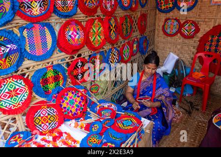 Narayanganj, Dacca, Bangladesh. 22 aprile 2024, Narayanganj, Dacca, Bangladesh: I lavoratori ricamano sapientemente ventilatori a mano con forme geometriche dai colori vivaci a Narayanganj, Bangladesh. Utilizzano bambù e filati colorati per creare ventilatori dal design complesso. Durante le estati calde, danno una brezza fresca che aiuta quando fa davvero caldo all'aperto in caso di distacco del carico. Ogni lavoratore può contare su 10 tifosi al giorno, ogni fan viene venduto per circa 1,20 USD alle fiere dei villaggi. Questa è diventata una professione tradizionale nella zona, fanno fan a mano da centinaia di anni. Credito: ZUMA Press, in Foto Stock