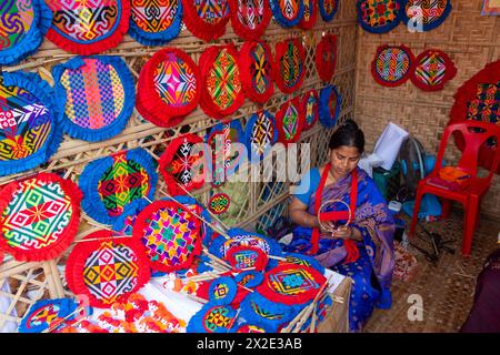 Narayanganj, Dacca, Bangladesh. 22 aprile 2024, Narayanganj, Dacca, Bangladesh: I lavoratori ricamano sapientemente ventilatori a mano con forme geometriche dai colori vivaci a Narayanganj, Bangladesh. Utilizzano bambù e filati colorati per creare ventilatori dal design complesso. Durante le estati calde, danno una brezza fresca che aiuta quando fa davvero caldo all'aperto in caso di distacco del carico. Ogni lavoratore può contare su 10 tifosi al giorno, ogni fan viene venduto per circa 1,20 USD alle fiere dei villaggi. Questa è diventata una professione tradizionale nella zona, fanno fan a mano da centinaia di anni. Credito: ZUMA Press, in Foto Stock