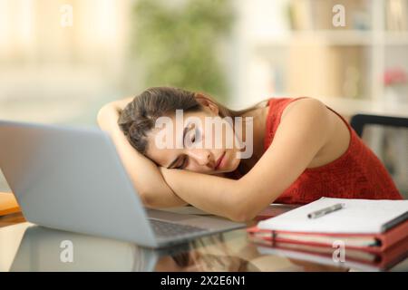 Studente stanco che dorme su un notebook a casa Foto Stock