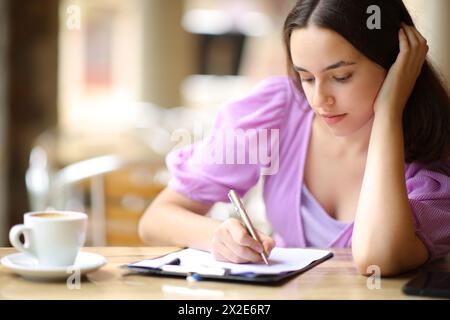 Donna seria che compila il modulo in una terrazza del ristorante Foto Stock