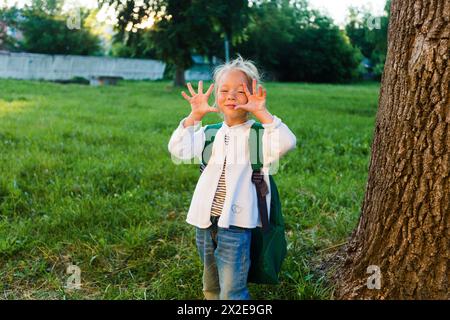 Una bambina fa facce e si diverte in un bellissimo parco estivo. Foto Stock