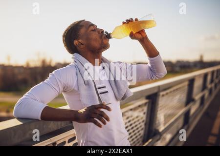 Ritratto di un giovane afroamericano che beve acqua e si rilassa dopo il jogging. Foto Stock