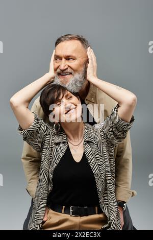 Un uomo e una donna di mezza età in un abbigliamento elegante si siedono a stretto contatto, trasudando un'aria di unità e tranquillità. Foto Stock